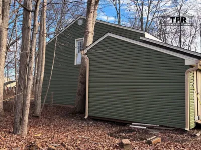 A technician installing white horizontal siding panels on the exterior wall of a residential home.