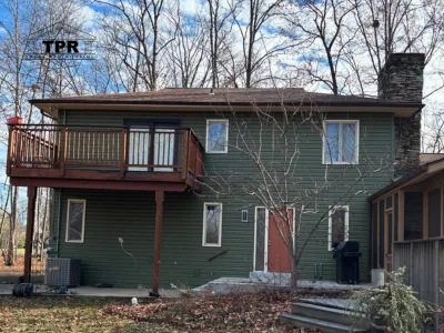 A technician installing white horizontal siding panels on the exterior wall of a residential home.