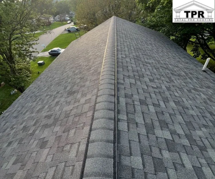 High-angle view of a newly installed gray shingle roof featuring a ridge vent running along the peak.